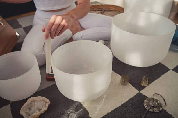 adult woman playing singing crystal bowl at home