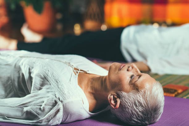 guided meditation therapy. senior woman meditating, lying on the floor